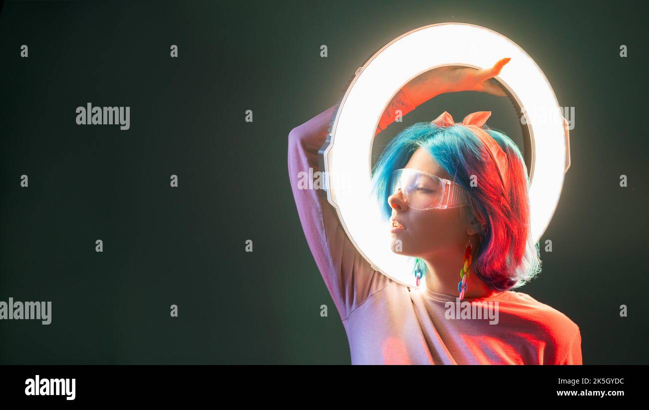 Cyberpunk-Frau. Synthesizer-Wave-Stil. Sci-Fi mit Neonlicht. Profil von stilvollen futuristischen Modell mit LED-Ring-Blitzlampe in rot leuchten isoliert auf dunklen Kopie s Stockfoto