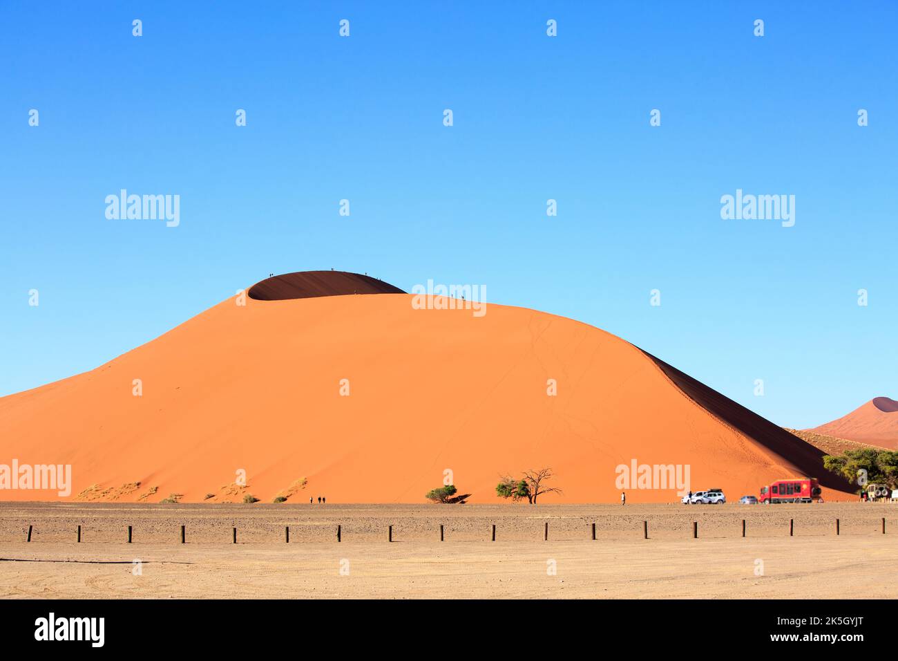 Düne 45 in der Namib Wüste mit Menschen klettern. Es gibt einen Parkplatz unterhalb der Düne, wo Touristen parken und sich ausruhen können. Stockfoto