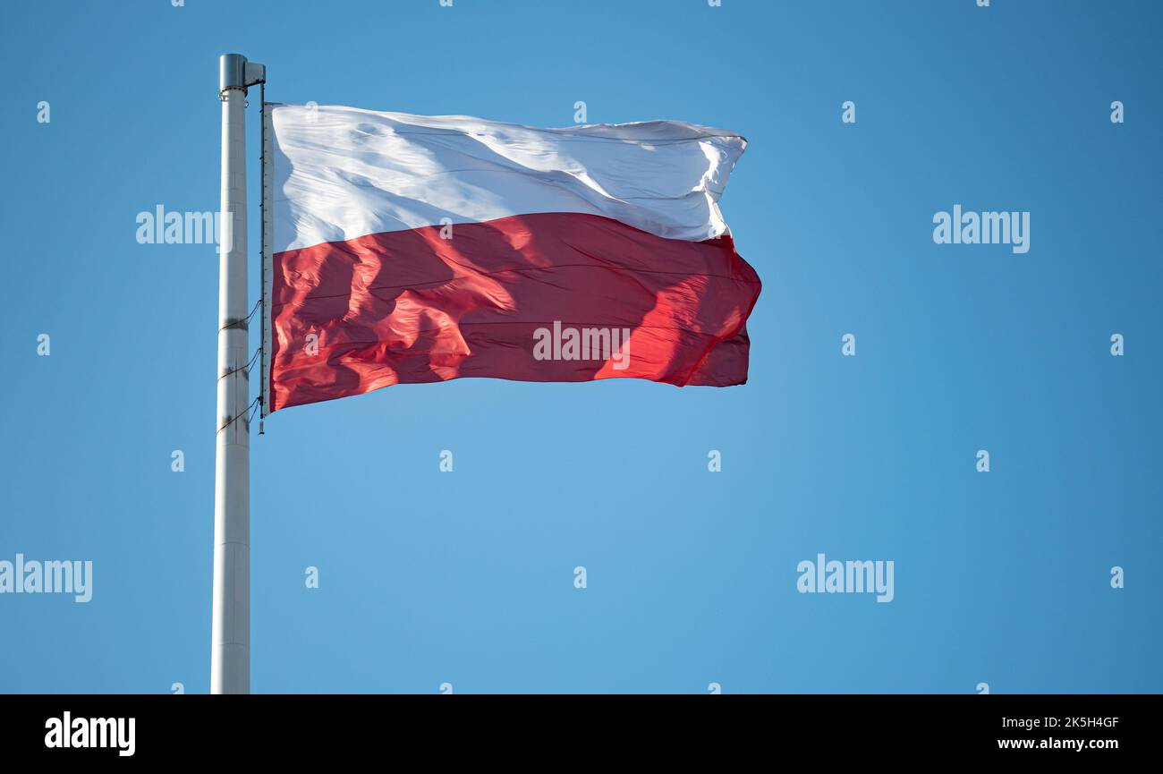 Polnische rote und weiße Flagge im Wind. Eine gewellte polnische Flagge wurde auf den Mast gehisst. Nationalfarben in Weiß und Rot. Stockfoto