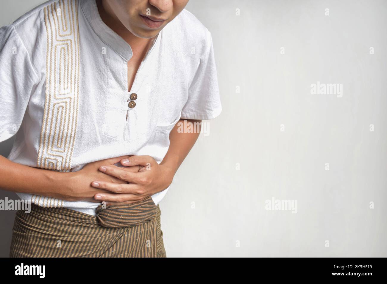 Asiatischer junger Mann, der an Schmerzen im oberen Bauchbereich leidet. Es kann durch Magenschmerzen, Enteritis, Colitis, Blinddarmentzündung, Hepatitis, Pankreatitis, Nahrung Stockfoto