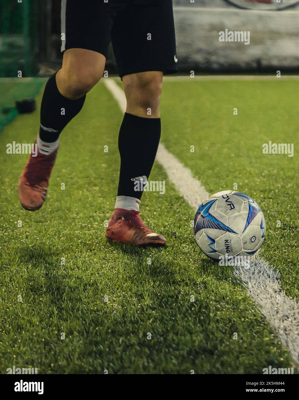 Nahaufnahme der Füße eines Fußballers und eines Balls auf einem Grasfeld Stockfoto