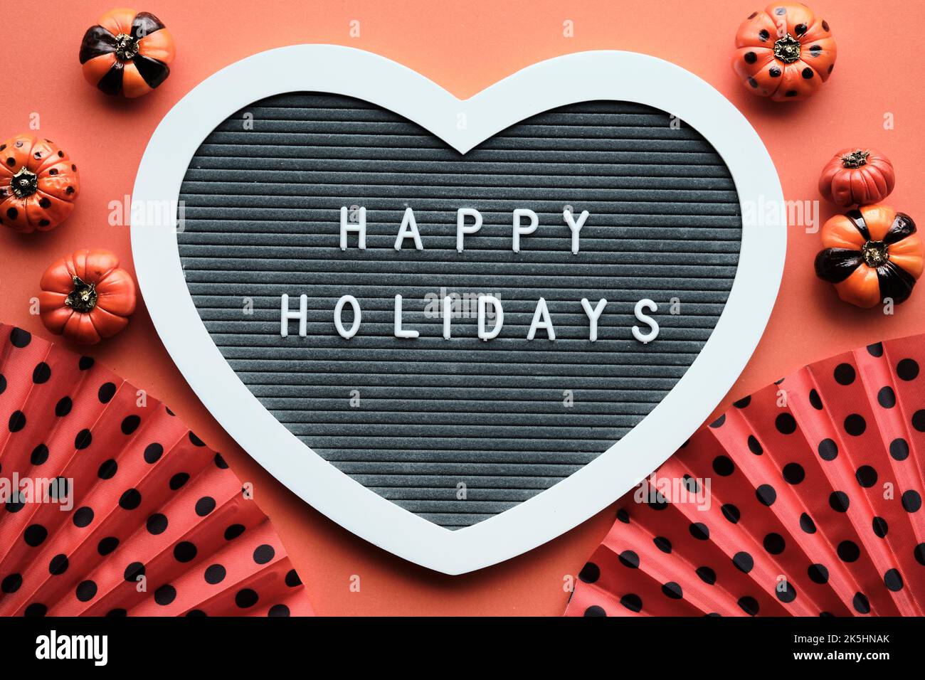 Halloween orange schwarz flach legen Hintergrund mit Dekorationen. Filzbriefbrett in Herzform mit Text Happy Holidays. Orangefarbene Fächer mit Tupfen Stockfoto