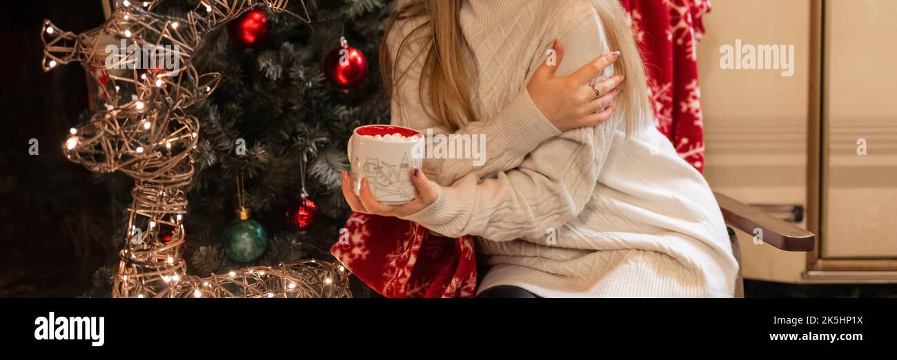 Junge ehrliche Frau in gestrickten gemütlichen Pullover halten in den Händen Tasse heiße Schokolade Getränk und umarmt sich entspannend Camping Outdoor Genuss glücklich n Stockfoto