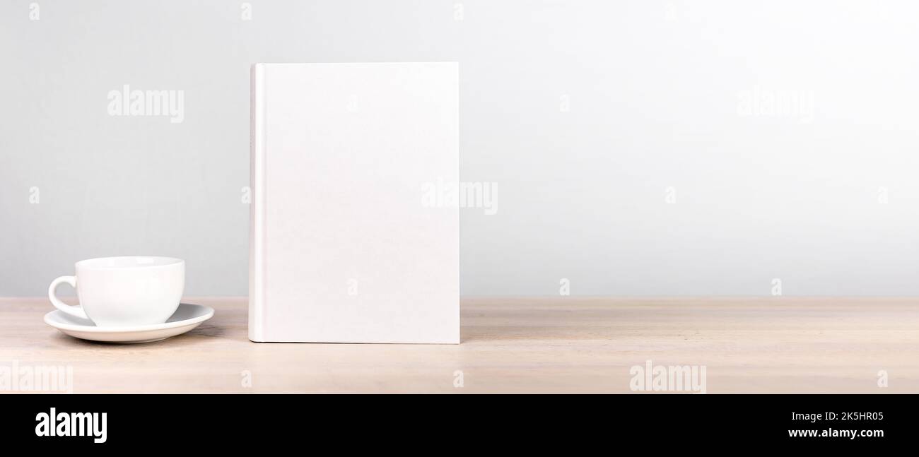 Buchmodell mit leerem unbelegtem Hardcover für Literaturwerbung. Banner mit Platz für Text und Kaffeetasse Stockfoto