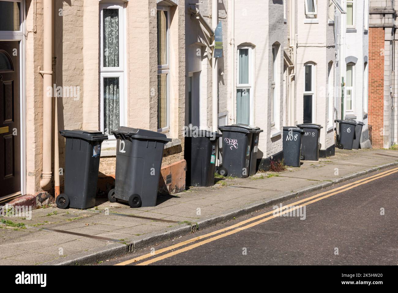 BOURNEMOUTH, Großbritannien - 08. Juli 2022. Reihe von Mülltonnen auf dem Bürgersteig vor den Häusern in einer Straße in Großbritannien Stockfoto