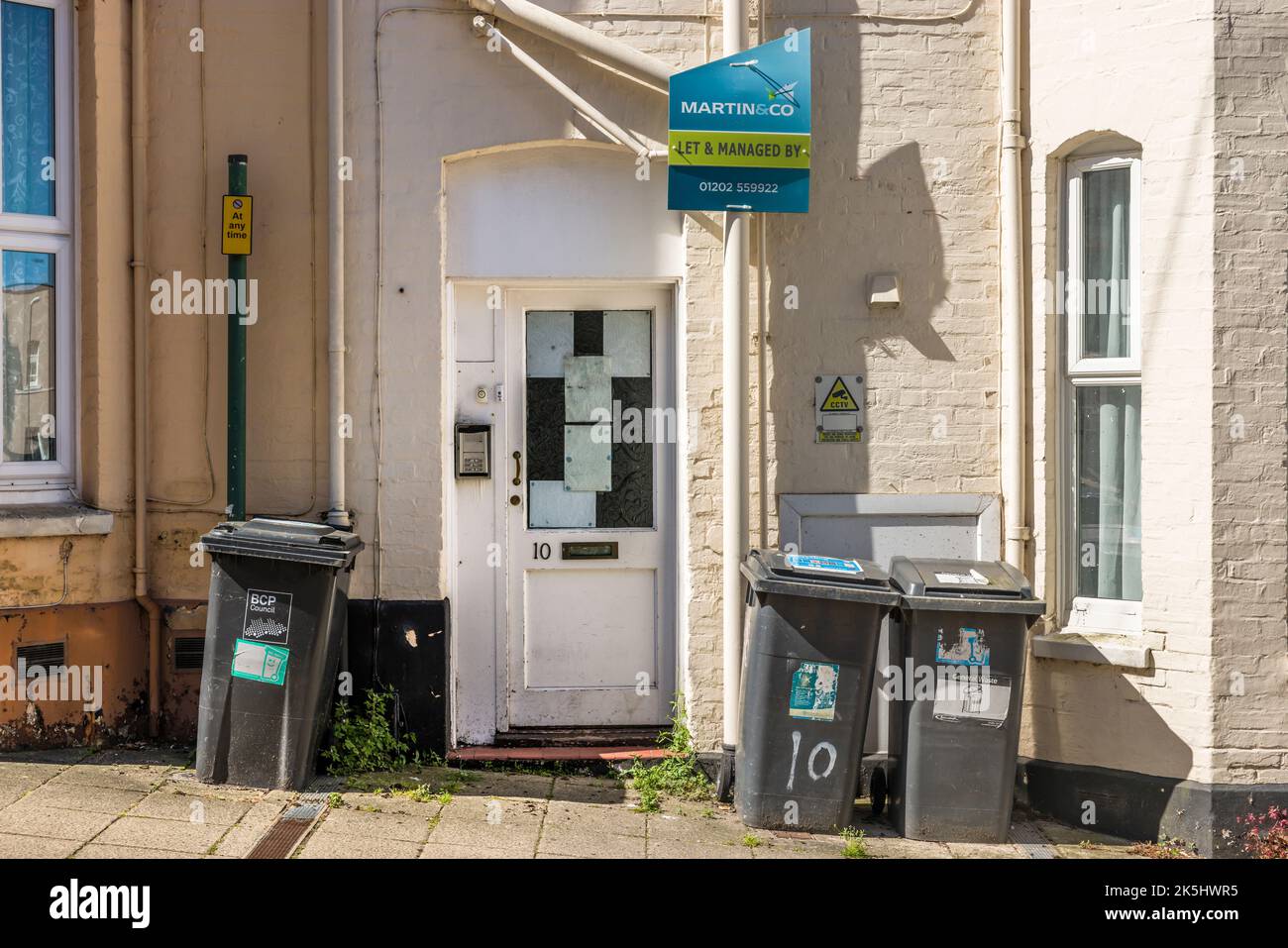 BOURNEMOUTH, Großbritannien - 08. Juli 2022. Außenansicht eines heruntergekommenen Hauses mit Wohnungen (Wohnungen) mit Mietschild und Mülltonnen Stockfoto