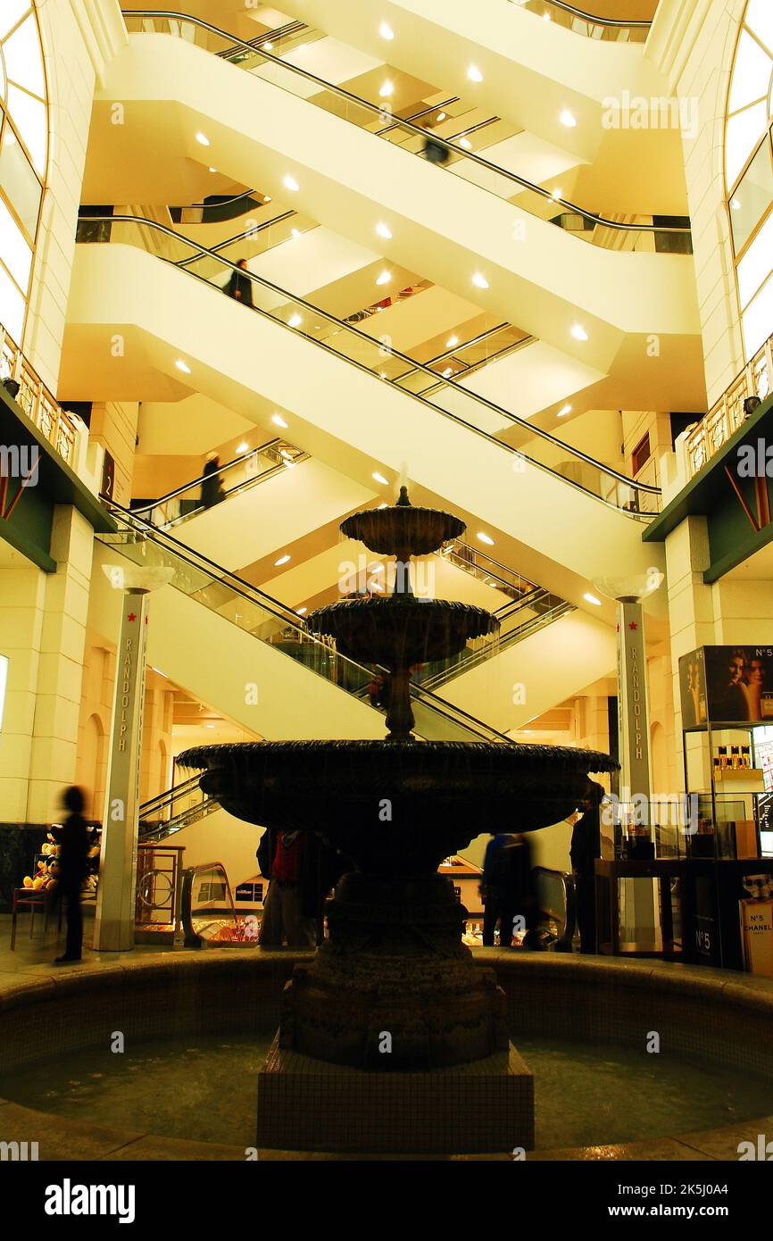 In der neueren Lobby des Kaufhauses Macy's, ehemals Marshall Fields, in Chicago, bilden Rolltreppen diagonale Linien über einem Wasserbrunnen Stockfoto