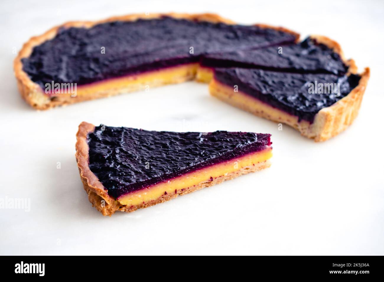 Brotscheibe mit Heidelbeere und Zitrone von oben gesehen: Geschichtete Blaubeer-Zitrone-Torte auf weißem Marmorboden Stockfoto