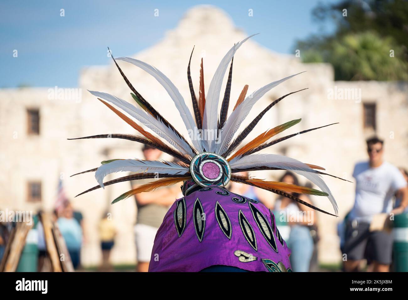 Eine indigene Frau in einem traditionellen Kopfschmuck tanzt während eines „Indigenous Dignity Day“-marsches vor dem Alamo in San Antonio, Texas. Stockfoto