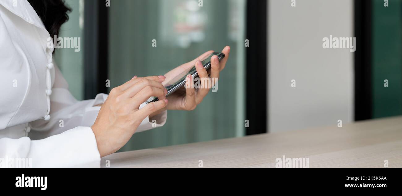 Frau mit einem Finger auf dem Bildschirm und einem Mobiltelefon im Büro Stockfoto