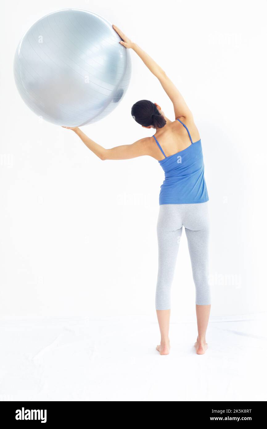 Arbeiten für ihre beste Gesundheit. Fit junge Frau trainieren, während sie einen Gymnastikball halten - Rückansicht. Stockfoto