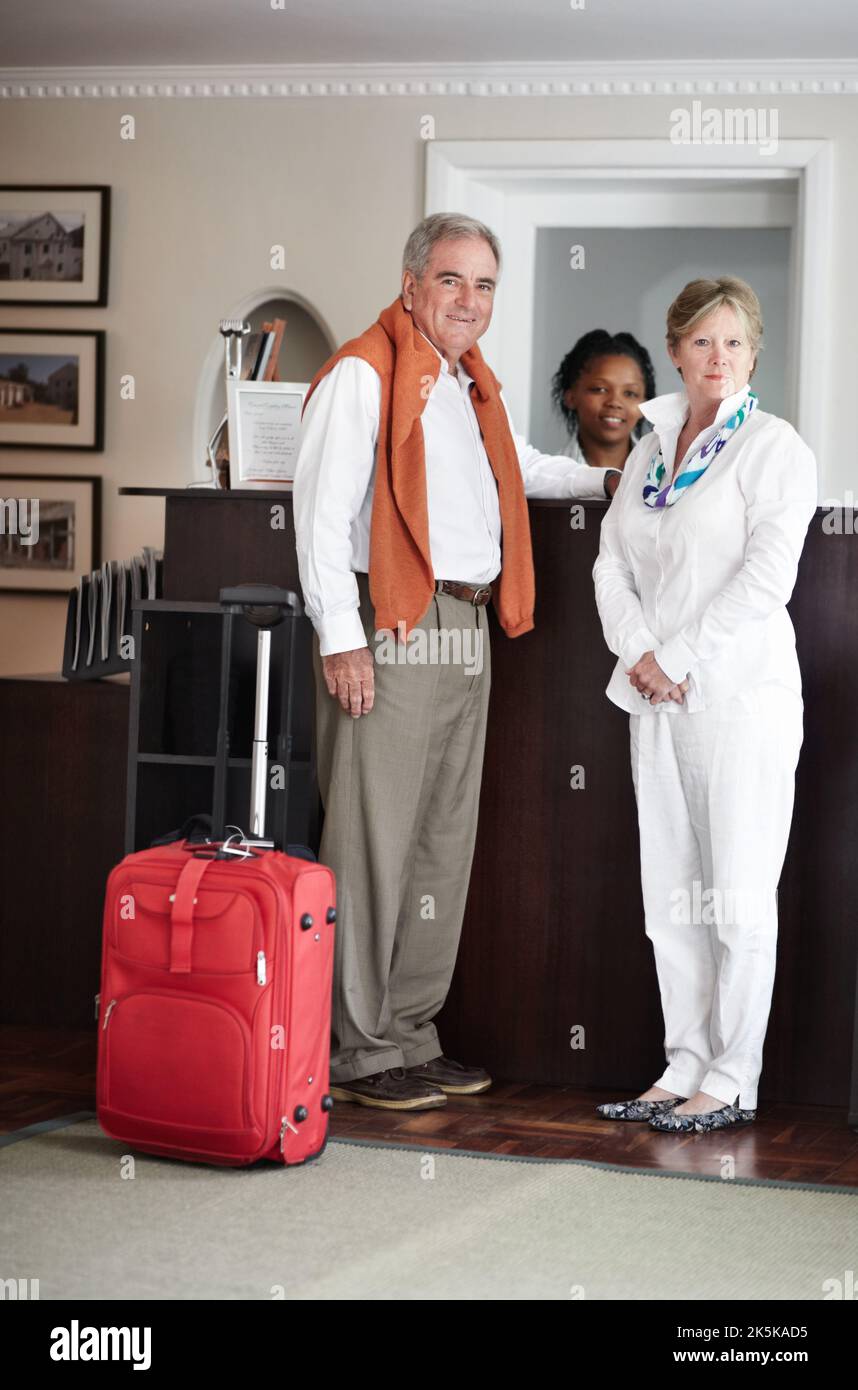 Einchecken an der Rezeption. Ein älteres Paar checkte an der Rezeption des Hotels ein. Stockfoto