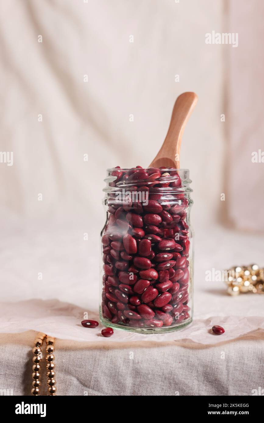 Vegane Proteinquelle. Rohbohnen im Glas auf grauen zerknittert Textilien. Gesunde vegetarische Ernährung und Lebensweise. Stockfoto