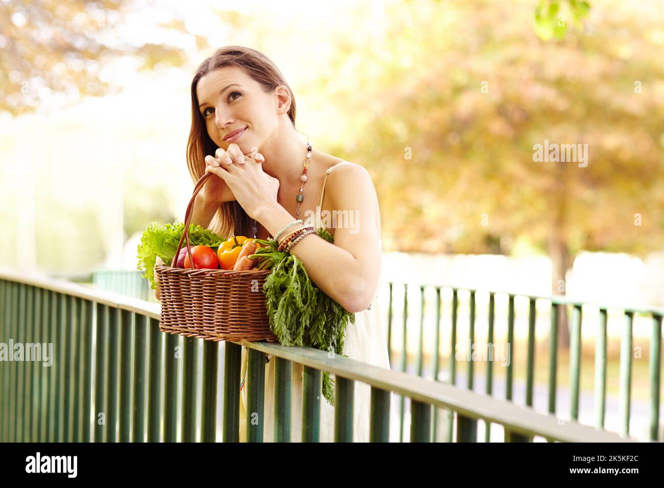 Es ist die Jahreszeit der Farbe. Eine attraktive junge Frau im Park an einem Herbsttag mit einem Korb mit Gemüse. Stockfoto