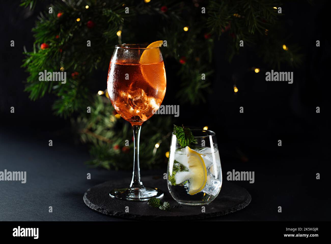 Cocktail namens Orangenspritz und Gin Tonic oder Moscow Mule in dunkler Partylaune. Feier-Szene mit dunklem Hintergrund. Weihnachts- oder Neujahrsparty dez Stockfoto