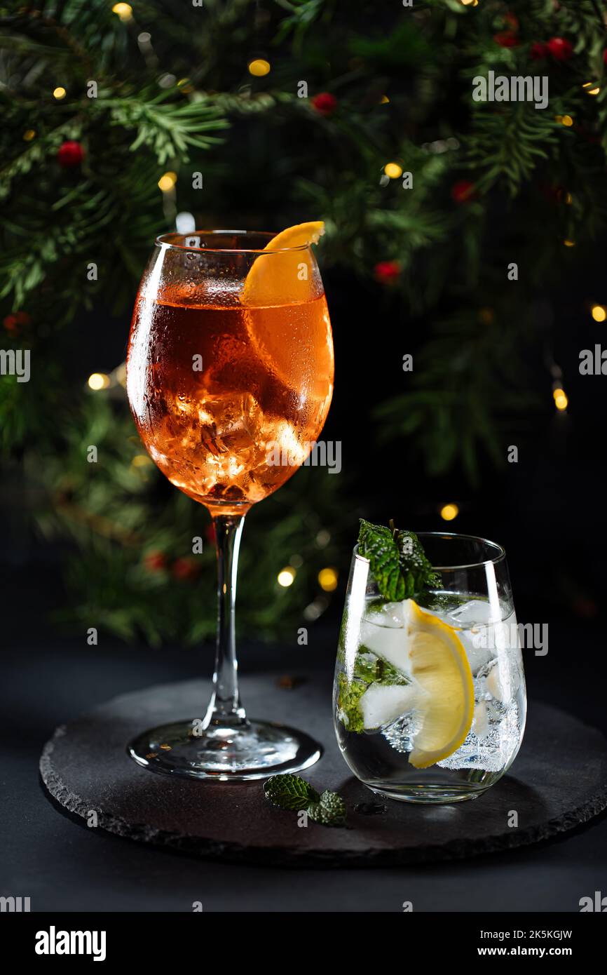 Cocktail namens Orangenspritz und Gin Tonic oder Moscow Mule in dunkler Partylaune. Feier-Szene mit dunklem Hintergrund. Weihnachts- oder Neujahrsparty dez Stockfoto