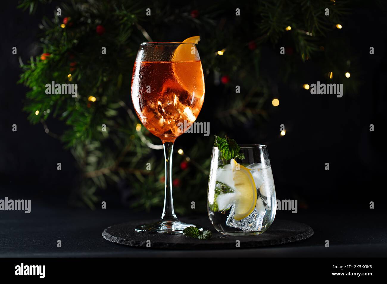 Cocktail namens Orangenspritz und Gin Tonic oder Moscow Mule in dunkler Partylaune. Feier-Szene mit dunklem Hintergrund. Weihnachts- oder Neujahrsparty dez Stockfoto