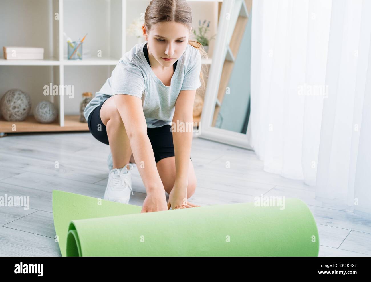 Aktive Kinder zu Hause Pilates Mädchen Abrollen Yoga-Matte Stockfoto