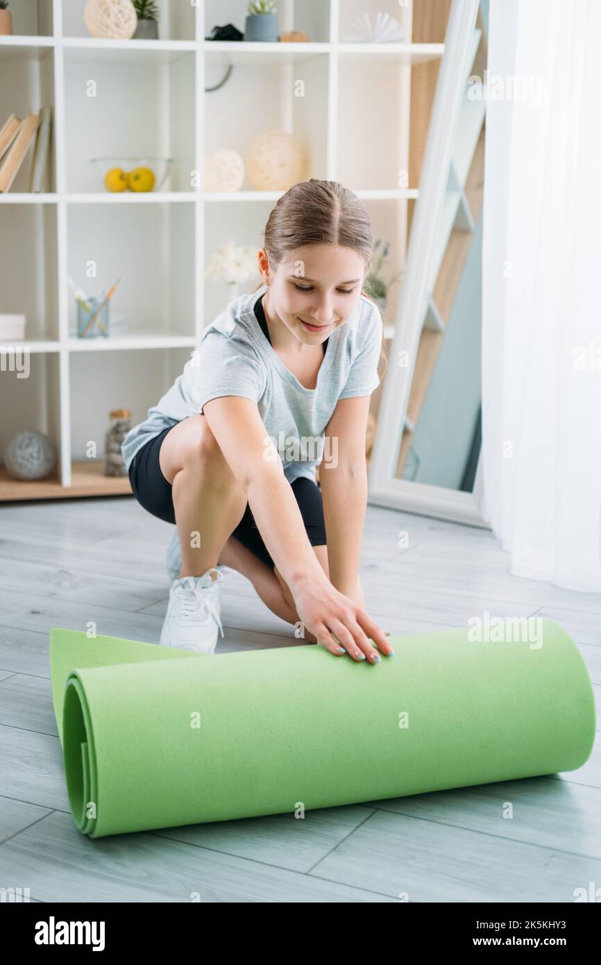 Aktive Kinder zu Hause Fitness-Studio Mädchen Abrollen Yoga-Matte Stockfoto