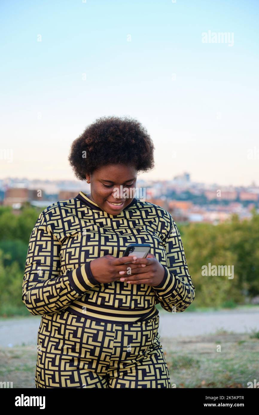 Junge Afrikanerin mit dem Smartphone auf der Straße. Stockfoto
