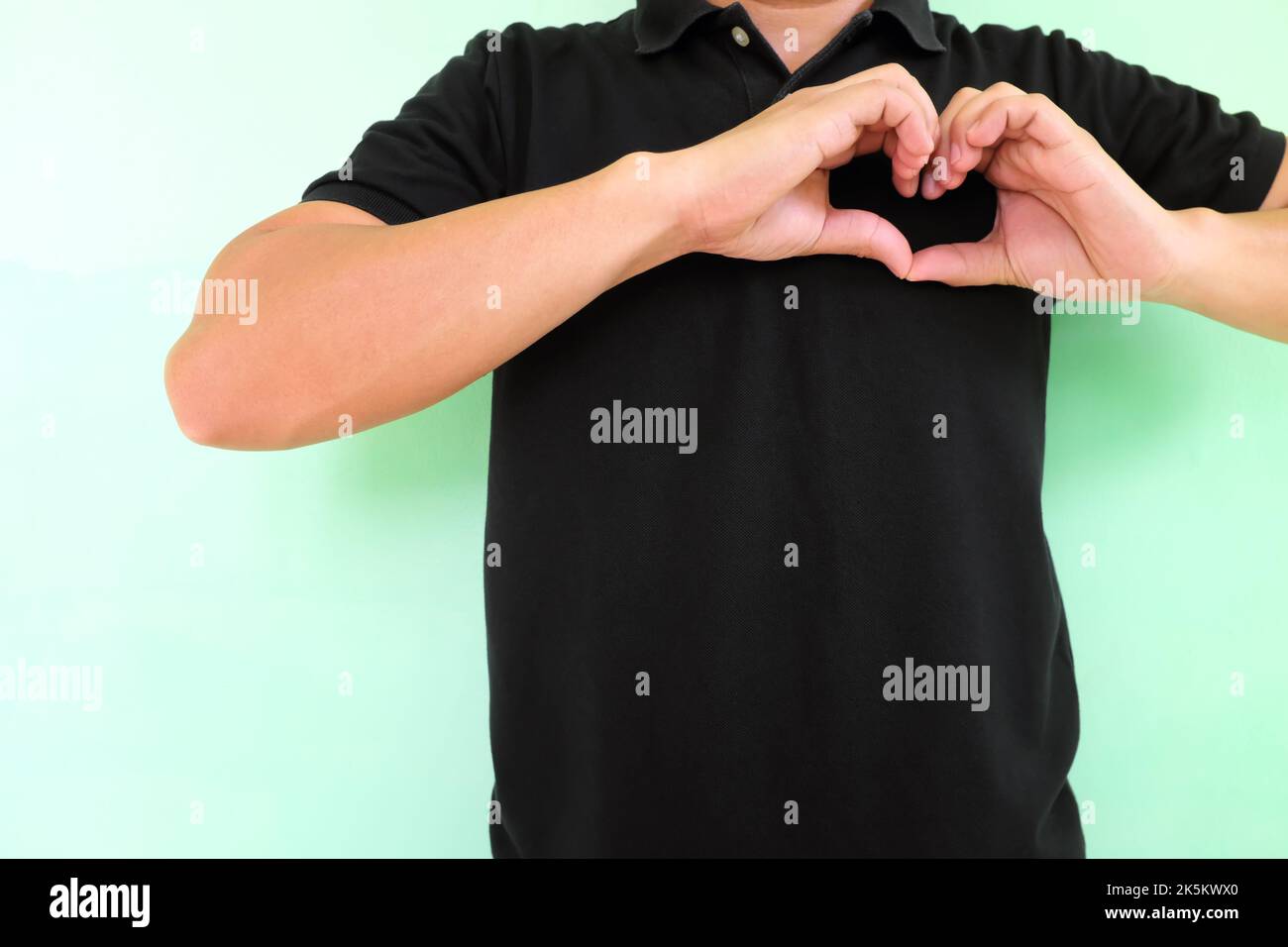 Verbreiten und zeigen Liebe und Zuneigung und gesundes Herz Konzept, junger asiatischer Mann mit herzförmigen Händen auf der Brust. Stockfoto