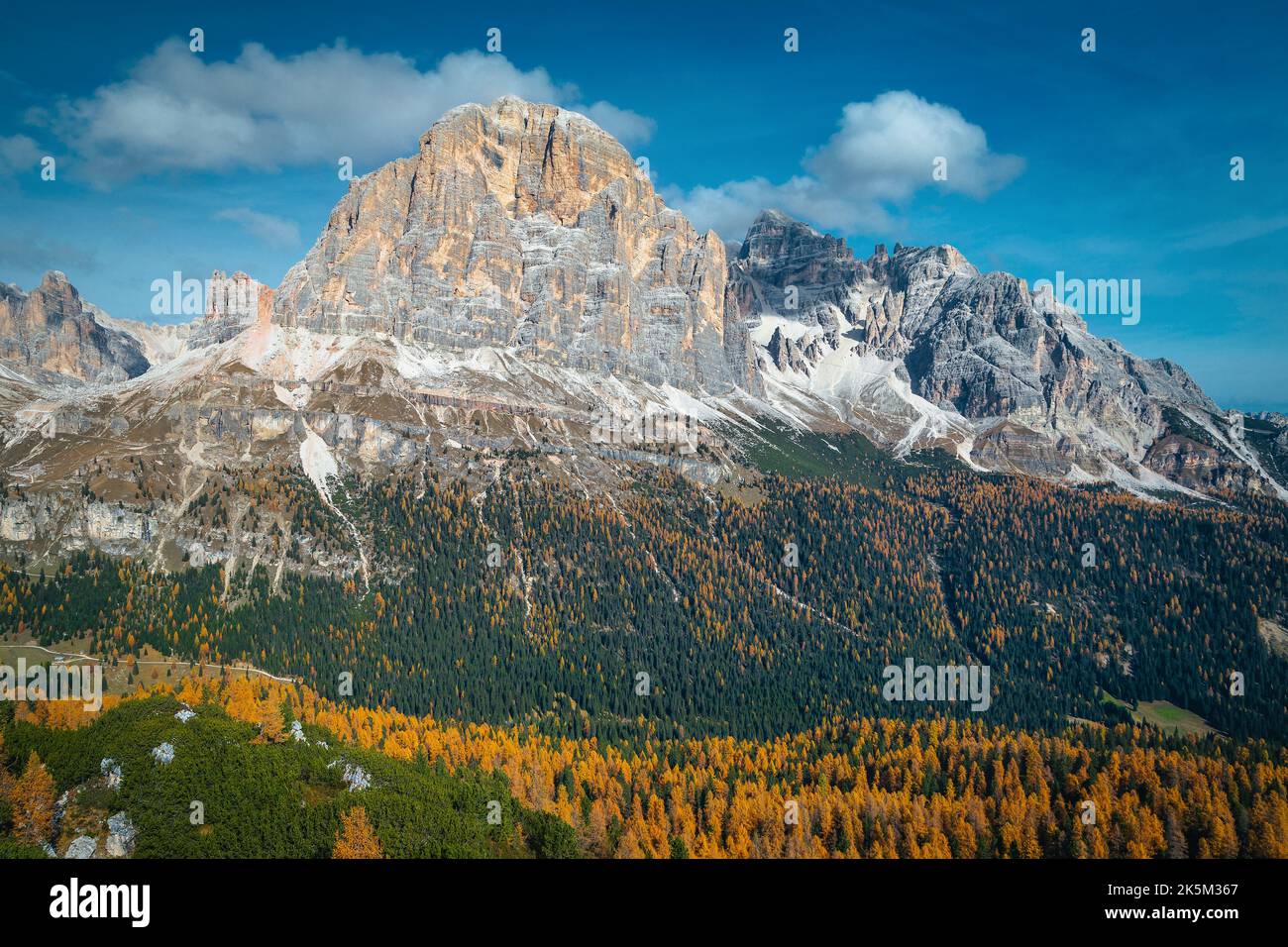 Malerische Herbst-Alpenszenerie mit buntem Lärchenwald an den Hängen und hohen Bergen im Hintergrund, Dolomiten, Italien, Europa Stockfoto