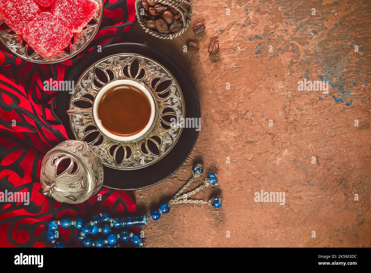 Türkische Kaffeetasse mit gerösteten Kaffeebohnen, türkischen Köstlichkeiten und Rosenkranz auf rustikalem Hintergrund. Draufsicht mit Kopierbereich. Stockfoto