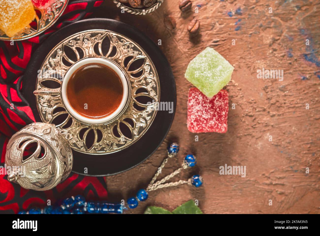 Türkische Kaffeetasse mit gerösteten Kaffeebohnen, türkischen Köstlichkeiten und Rosenkranz auf rustikalem Hintergrund. Draufsicht mit Kopierbereich. Stockfoto