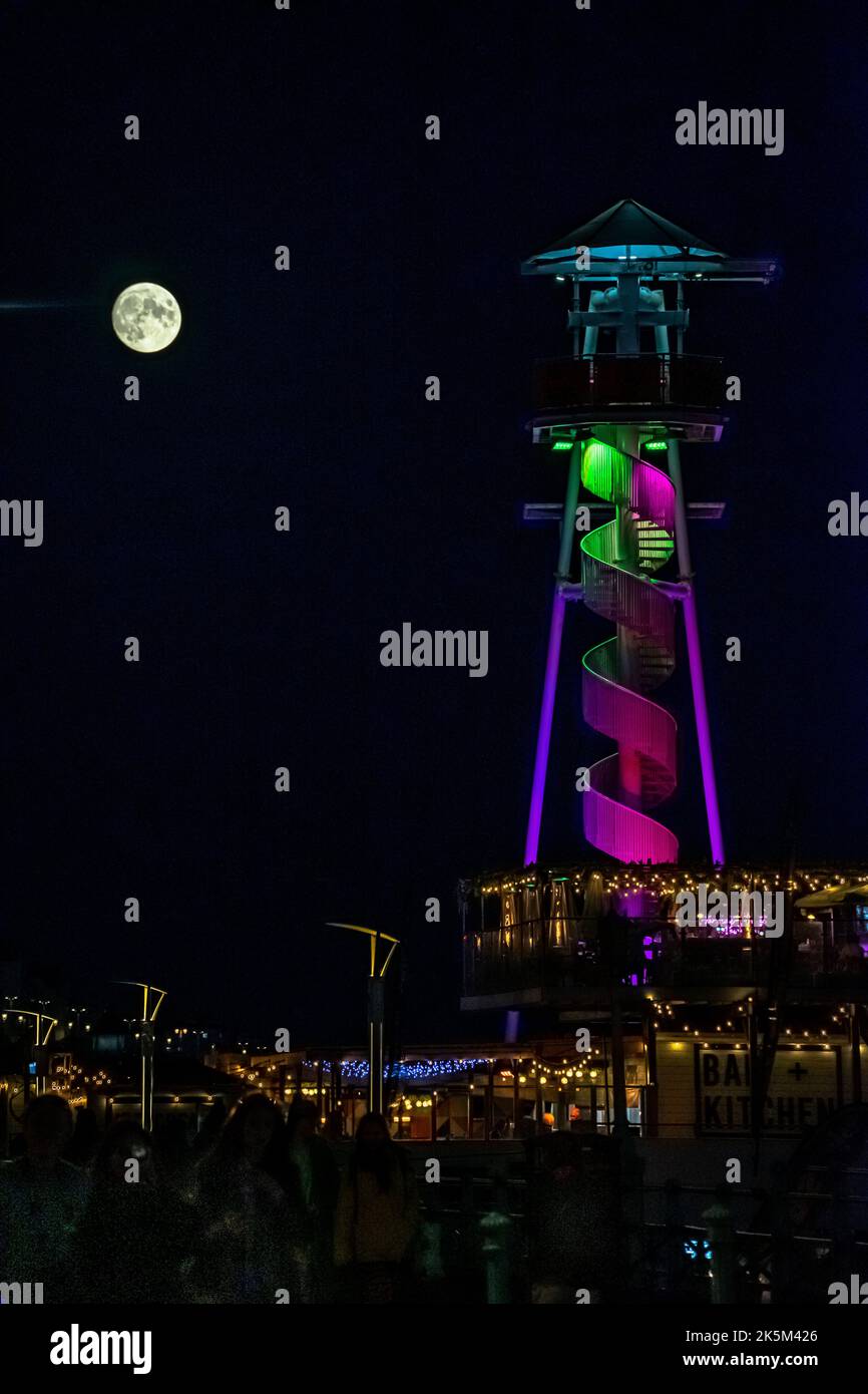 Brighton, East Sussex, England. 08. Oktober 2022. Ein (97,5%) Vollmond erhebt sich über dem Strand in Brighton und wird hier hinter dem Reißleine vom Brighton Pier aus gesehen glühend gesehen.©Sarah Mott / Alamy Live News. Stockfoto