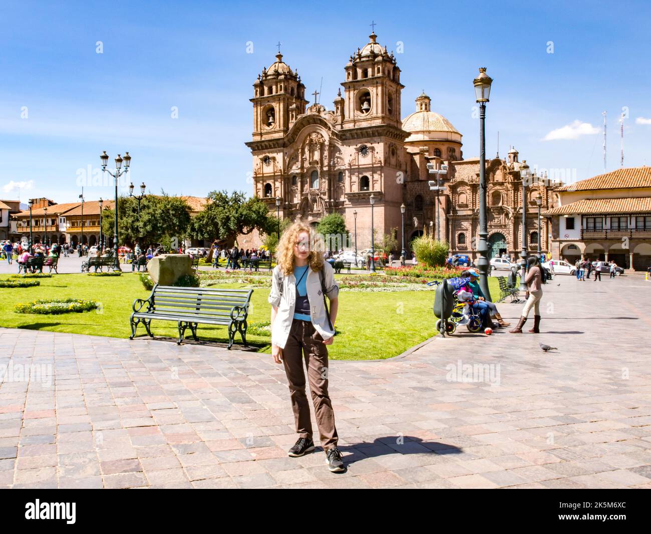 Cusco, Peru - Mai 2016: Junge Frau auf der 'Plaza de armas' im Zentrum von Cuzco. Die Kathedrale im Hintergrund sichtbar. Lateinamerika. Stockfoto