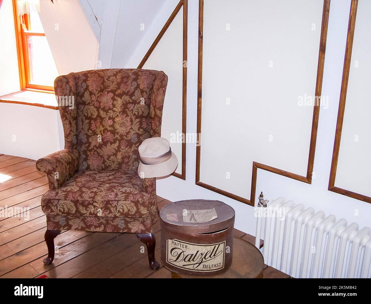 Altmodischer viktorianischer Wingback-Stuhl mit Hut und Hutkasten in einem runden Schlafzimmer Stockfoto