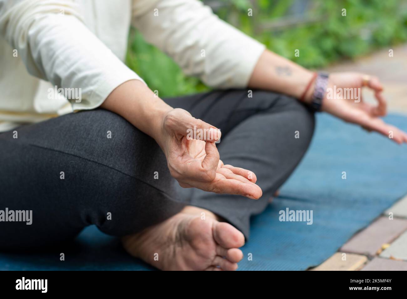 Nahaufnahme Frau Mudra Handbewegung beim Yoga Entspannen in Lotusposition auf Matte sitzend. Im Freien. Meditation in der Natur üben. Hintergrundbild. Stockfoto