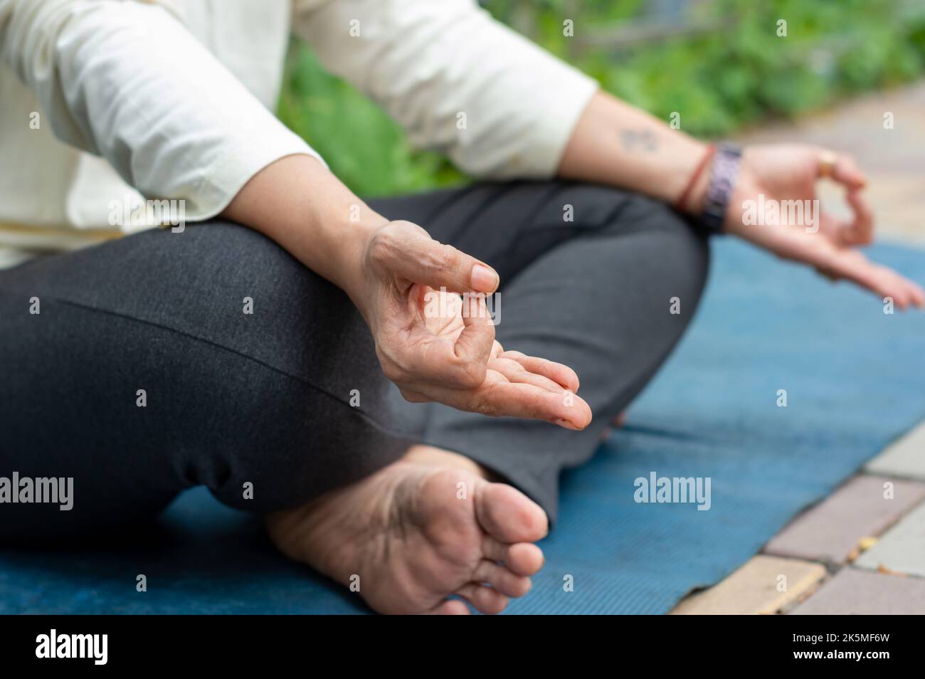 Nahaufnahme Frau Mudra Handbewegung beim Yoga Entspannen in Lotusposition auf Matte sitzend. Im Freien. Meditation in der Natur üben. Hintergrundbild. Stockfoto