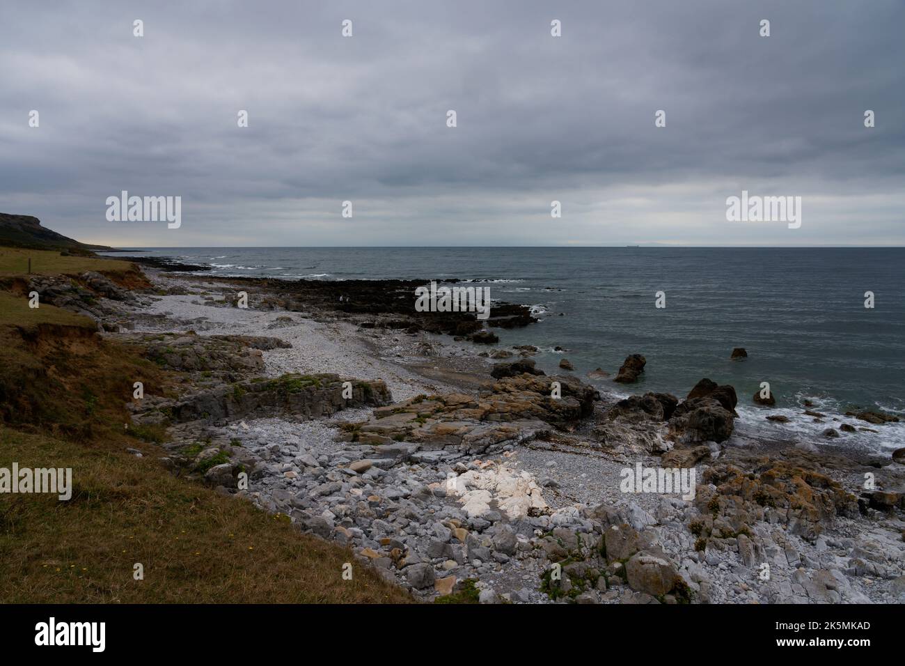 Felsen von vielen Farben an den Ufern der Oxwich Bay an einem grauen Sommerhimmel. Stockfoto