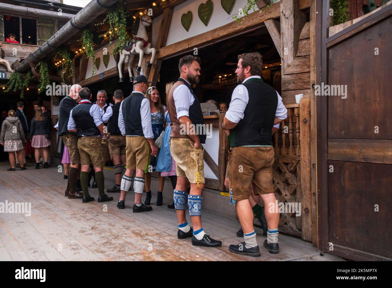 Besucher in traditioneller Kleidung vom Oktoberfest in München sprechen vor einer der Brauereien. Stockfoto