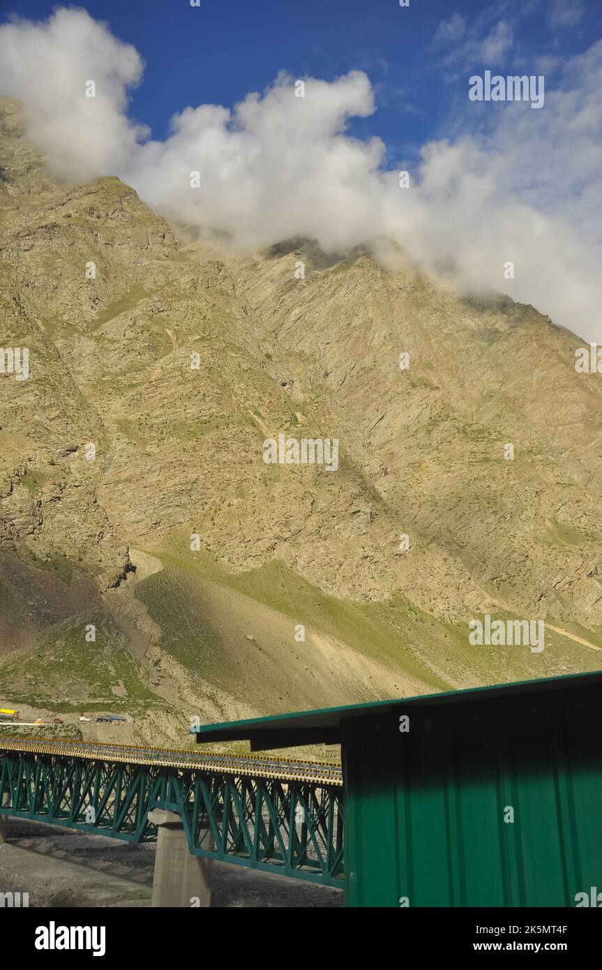 Trockener Berg bedeckt mit Wolken mit der längsten Stahlbrücke auf der Manali-Leh Autobahn in Darcha, Lahaul und Spiti, Himachal Pradesh, Indien Stockfoto