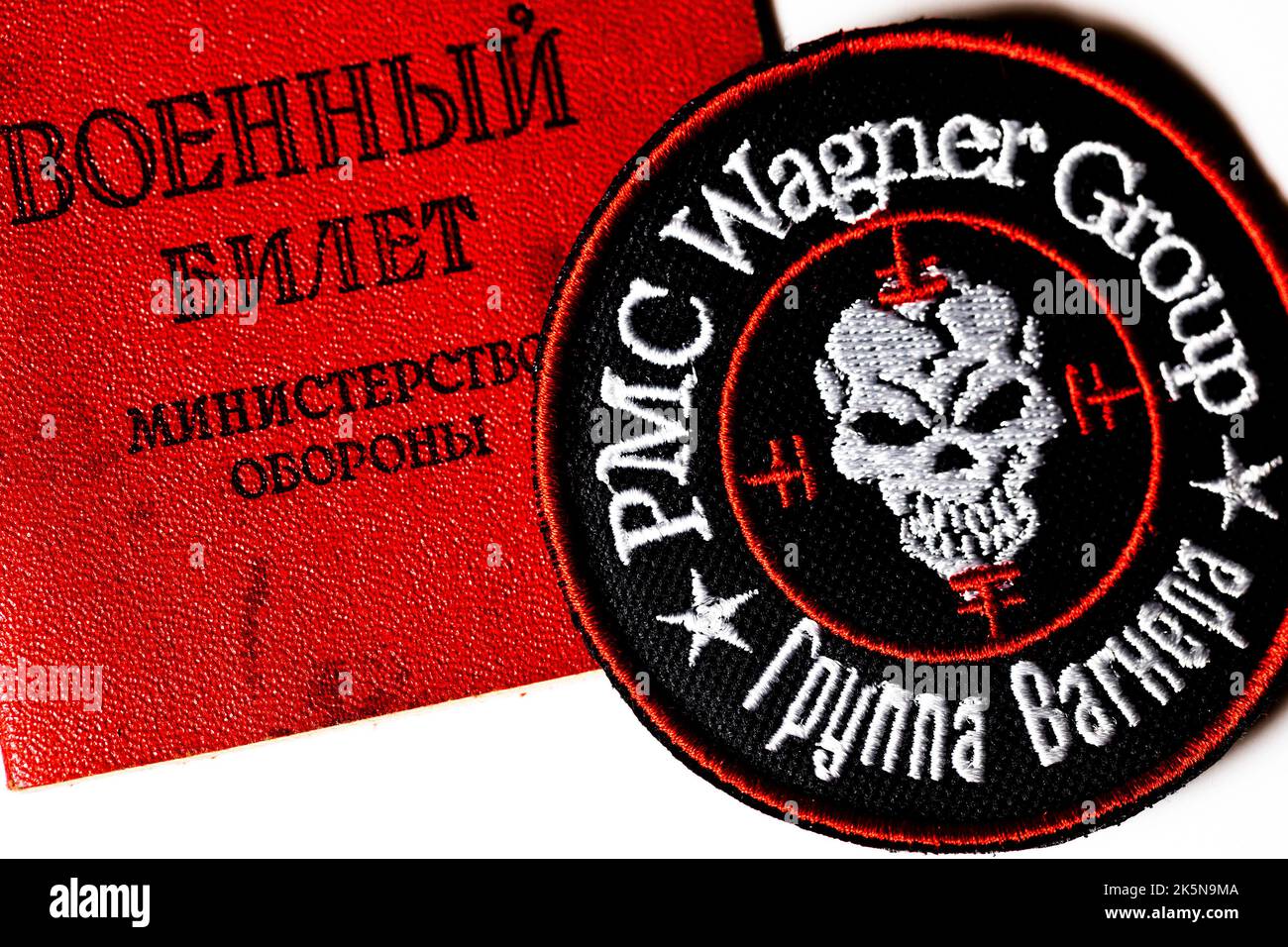 Ansicht eines Logos der russischen privaten Militärfirma 'Wagner Group' und eines russischen Militärausweises auf weißem Hintergrund Stockfoto