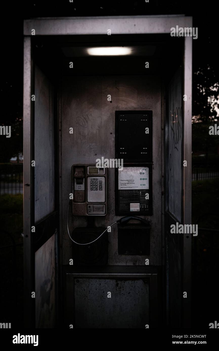In einer britischen Stadt ist eine Telefonbox zu sehen, bei der der Empfänger aus dem Haken kommt Stockfoto