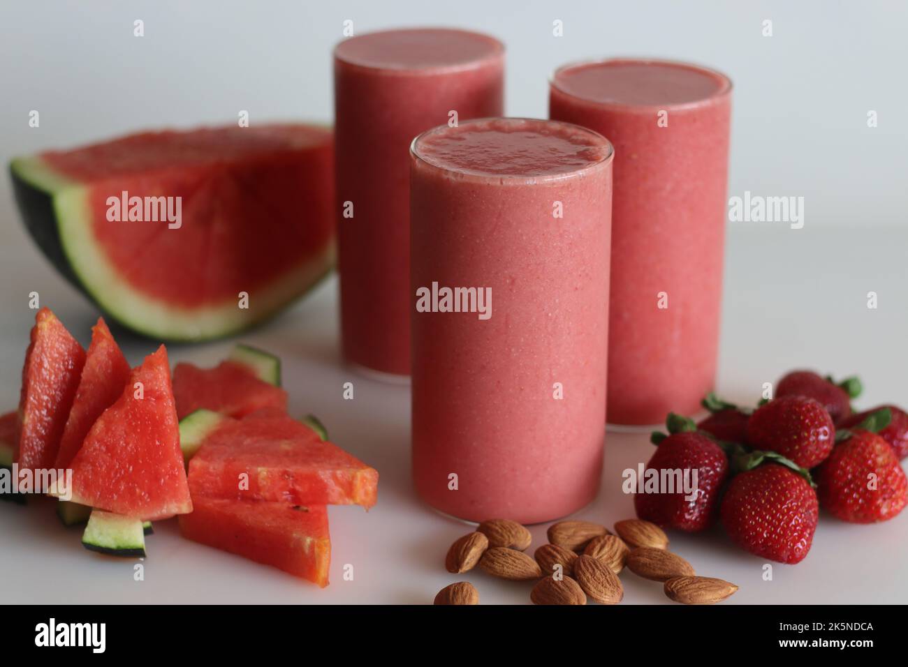 Erdbeer-Smoothie mit Wassermelone. Sommergetränk aus Wassermelone und frischen Erdbeeren in Mandelmilch. Aufgenommen auf weißem Hintergrund zusammen mit Wassermelone Stockfoto