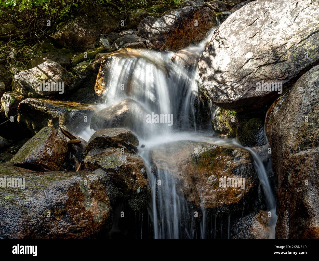 Wafer Kaskaden über Felsen bilden einen kleinen Wasserfall Stockfoto