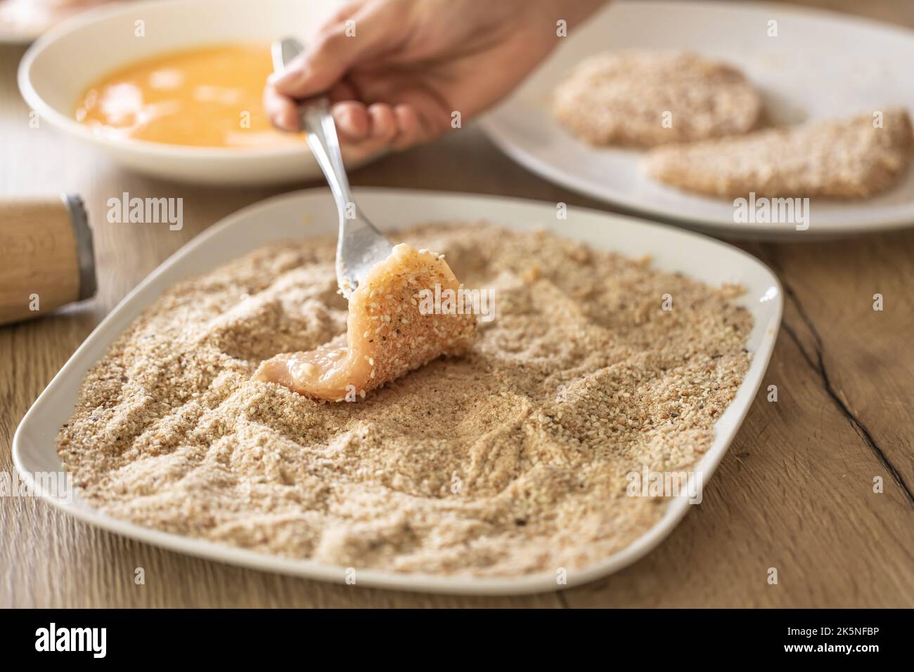 Letzte Stufe der Beschichtung von Fleisch in Semmelbröseln während der Herstellung Schnitzel. Stockfoto