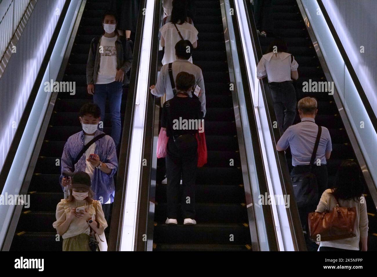 Personen, die auf einer Rolltreppe stehen Stockfoto