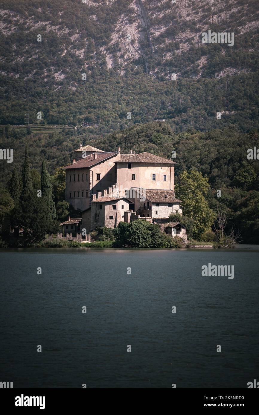 Eine vertikale Aufnahme eines alten Schlosses, umgeben von immergrünen Bergen mit einem See im Vordergrund Stockfoto