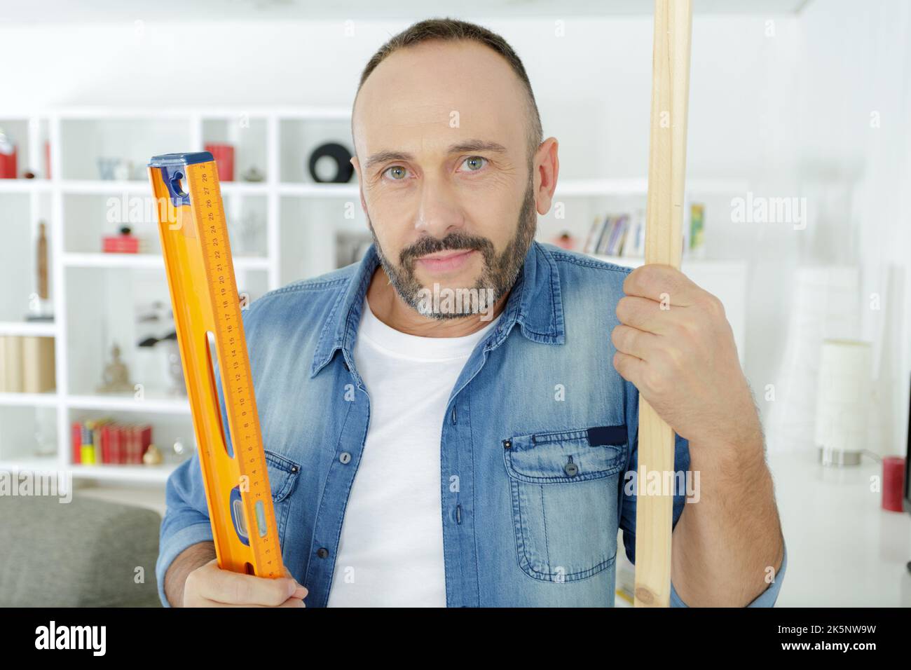 Nahaufnahme des Mannes mit dem Niveau auf Holzbrett Stockfoto