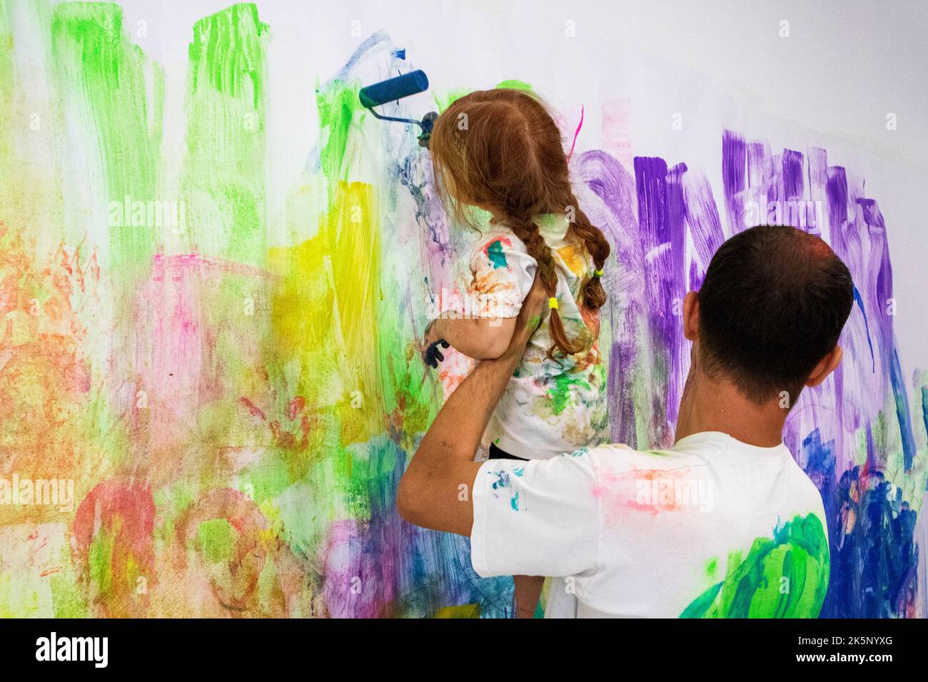 Vater und Tochter malen die Wand in verschiedenen Farben Stockfoto