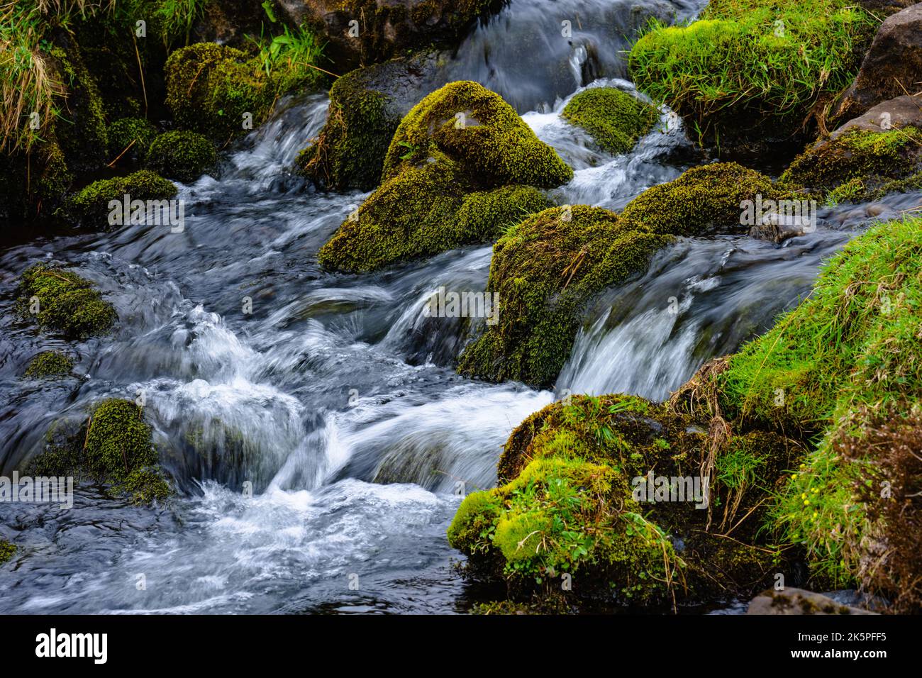Ein wunderschöner Wasserfall, der die mit Moos bedeckten Felsen hinunterfließt Stockfoto