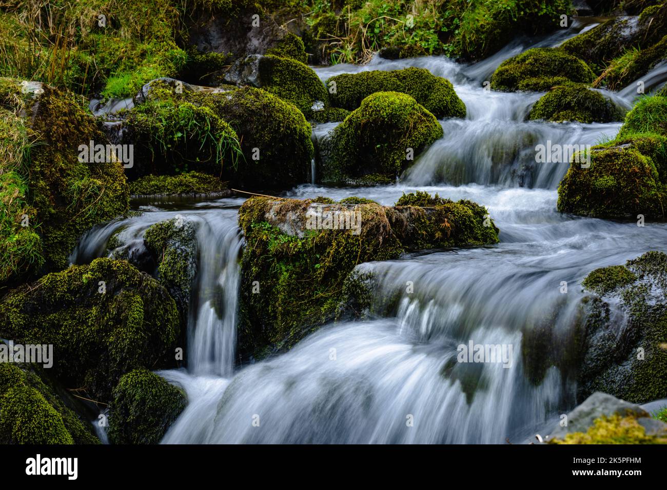Ein wunderschöner Wasserfall, der die mit Moos bedeckten Felsen hinunterfließt Stockfoto