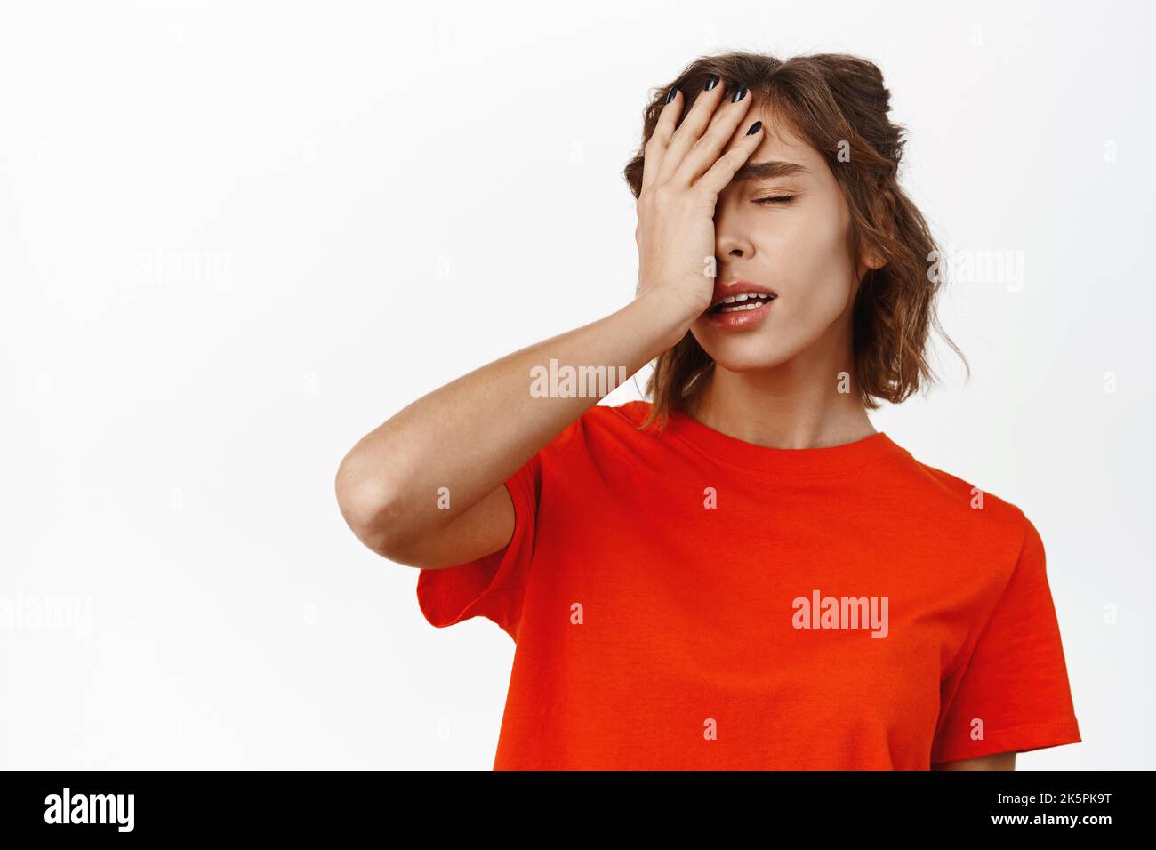 Facepalmmädchen. Enttäuschte junge Frau, die müde aussieht, mit der Hand ins Gesicht schlagen, bekümmert und aufgeregt stehen, weißer Studiohintergrund Stockfoto