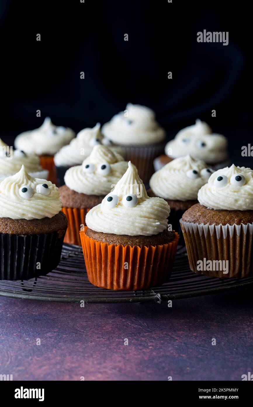 Kürbis-Gewürz-Cupcakes auf einem Kühlgestell aus Metall, vor schwarzem Hintergrund. Stockfoto