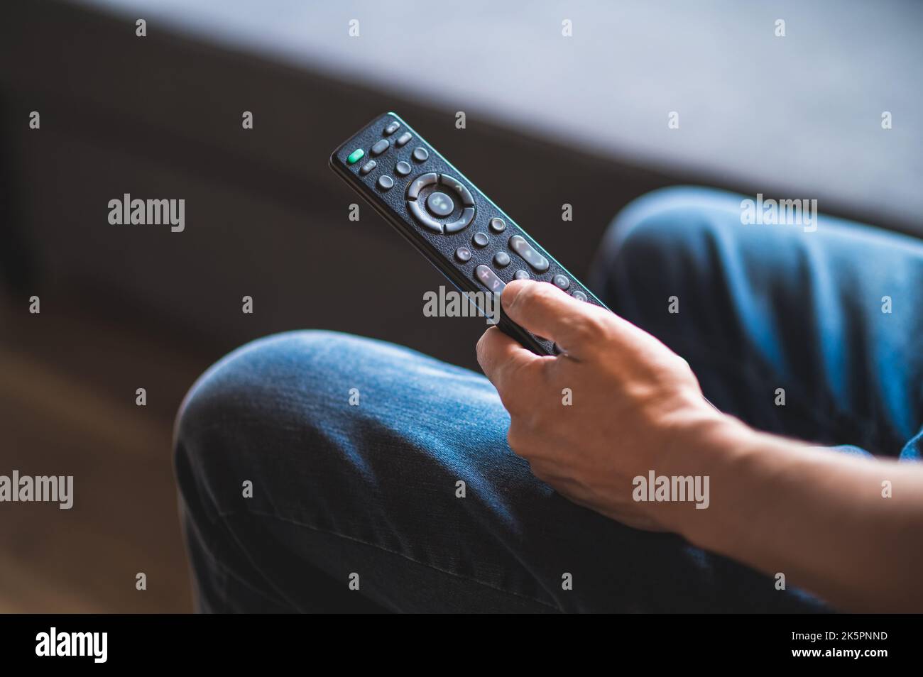 Mann verbringt Zeit zu Hause und swithin auf tve mit einer tv-Fernbedienung Stockfoto